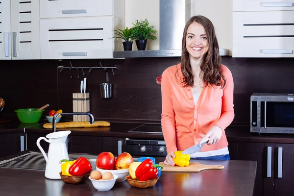 Mujer joven picando pimienta en la cocina — Foto de Stock