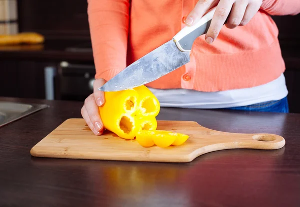Jovem mulher cortando pimenta na cozinha — Fotografia de Stock