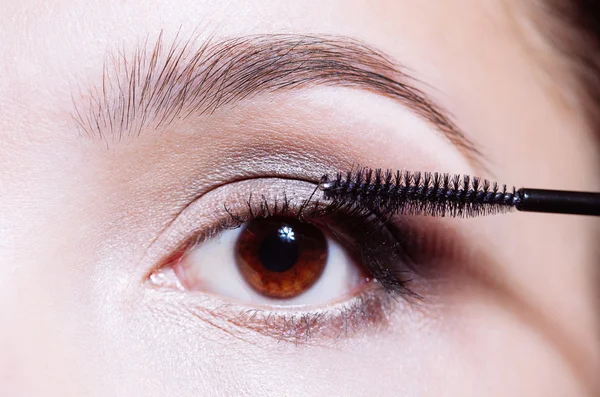 Woman applying mascara on her eyelashes — Stock Photo, Image