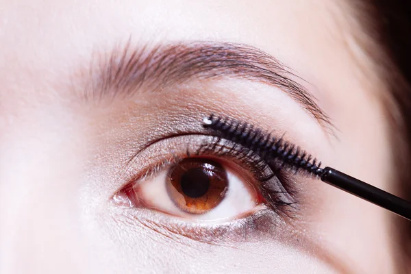 Woman applying mascara on her eyelashes — Stock Photo, Image
