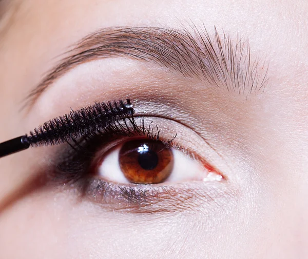 Woman applying mascara on her eyelashes — Stock Photo, Image