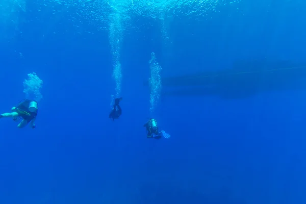 Группа дайверов возле лодки под водой — стоковое фото