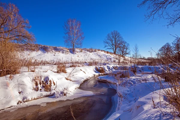 Лесная река со снегом ранней весной — стоковое фото
