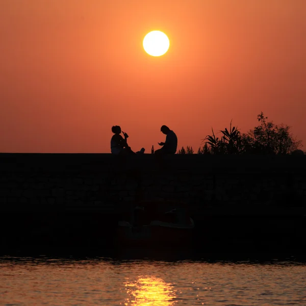 Západ slunce scéna s lidmi siluety, moře a slunce silniční — Stock fotografie