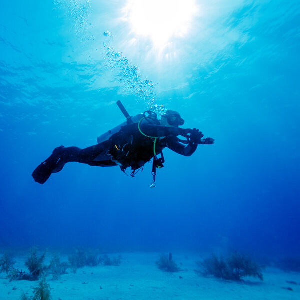 Силуэт водолаза с солнечным диском позади
