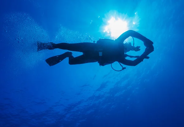 Silhouette of diver with sun disk behind — Stock Photo, Image