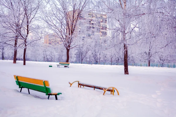 Зимний парк со снежными скамейками — стоковое фото