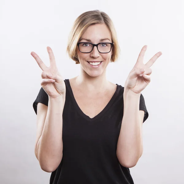 Beautiful young woman making a victory sign — Stock Photo, Image