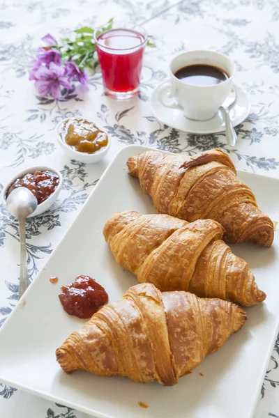 Croissants na mesa com geléia, suco de laranja e café — Fotografia de Stock