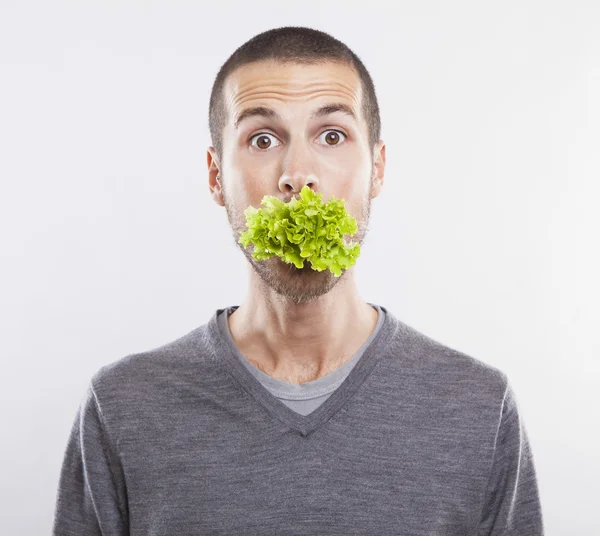 Молодой человек с салатом во рту — стоковое фото