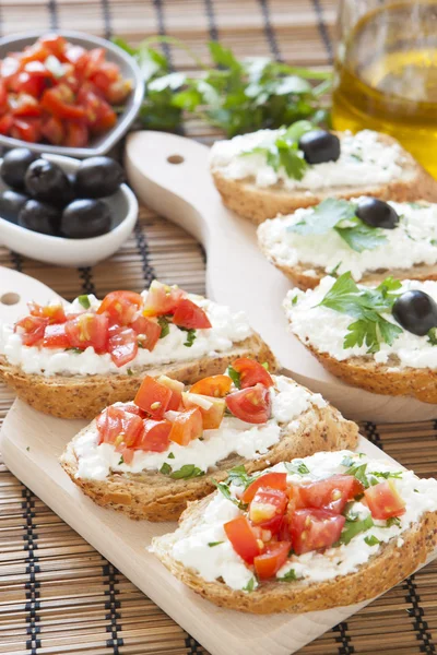 Crostini with cottage cheese, parsley, tomato and olives on cutt — Stock Photo, Image