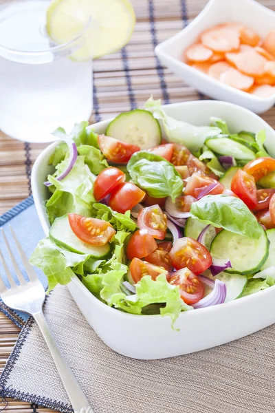 Frischer grüner Salat mit Salat, Gurken, Tomaten und roten Zwiebeln. — Stockfoto