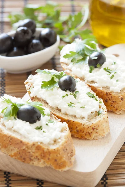 Crostini with cottage cheese, parsley and olive — Stock Photo, Image