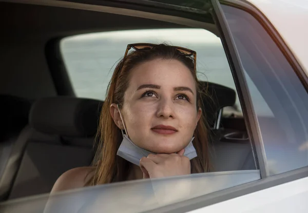 Ευτυχισμένη Νεαρή Όμορφη Γυναίκα Μάσκα Προσώπου Κάθεται Στο Αυτοκίνητο Κοιτάζοντας Εικόνα Αρχείου