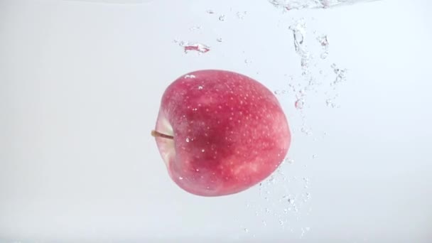 Een Sappige Rode Appel Valt Het Water Met Spatten Bellen — Stockvideo