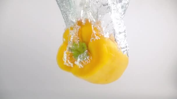 Eine Gelbe Paprika Fällt Mit Spritzern Und Blasen Zeitlupe Ins — Stockvideo