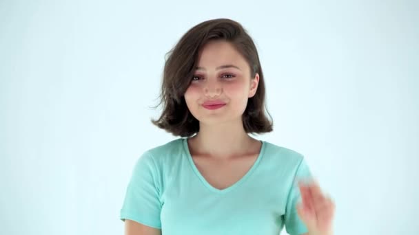 年轻女子在白人背景上表现出胜利或和平的标志 快乐的女孩伸出两根手指 — 图库视频影像