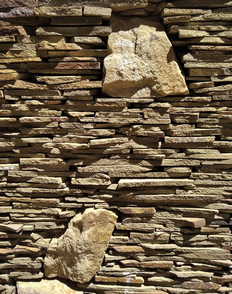 Arkaplan düz ve büyük doğal bej topaklar ve düz olmayan yüzeylerden oluşur. Duvar parlak ışıkla aydınlatılmış.. 