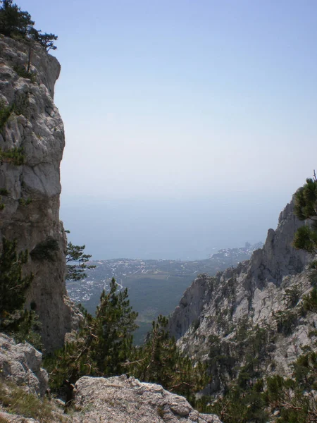 Dik kayalıkları olan kayalıklar çam ağaçlarıyla kaplıdır. Vadinin çok aşağısında, açık bir sis perdesi altında. Hepsi güzel bir gökyüzünün arka planına karşı.
