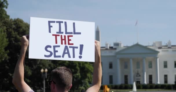 Man Holds Fill The Seat Sign in Front of White House — 비디오