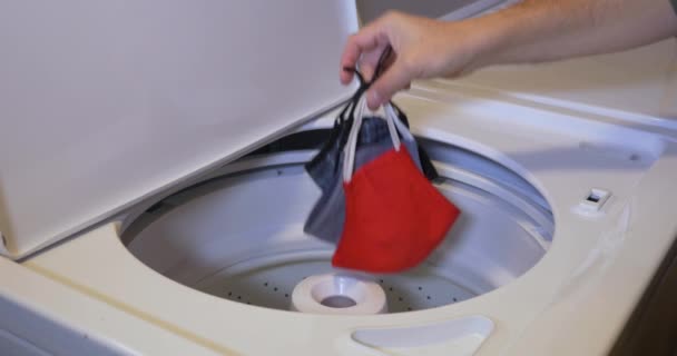 El hombre pone máscaras de tela en la lavadora — Vídeos de Stock