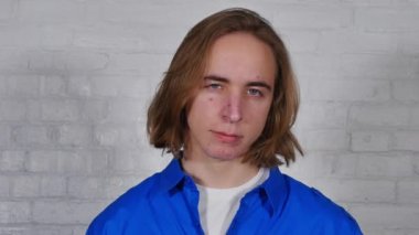 Üzgün bir genç adam kameraya benziyor.