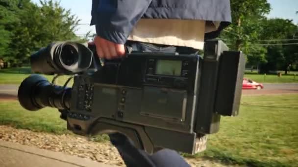 Uno scatto a basso angolo di un cameraman che porta la sua videocamera ad una produzione . — Video Stock