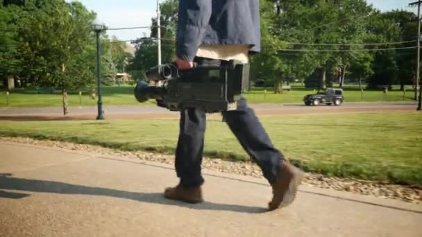 En låg vinkel skott av en kameraman som bär hans video kamera till en produktion. — Stockvideo