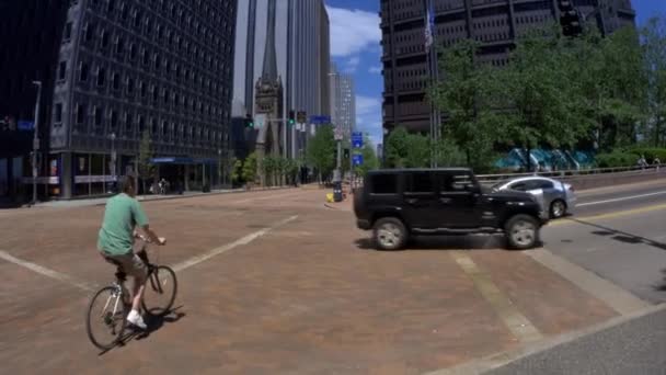 4 k Biker kruisen straat in Pittsburgh kantelen tot ons staal gebouw 4402 — Stockvideo