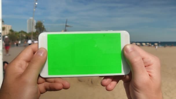 A man holds a smartphone with green screen — Stock Video