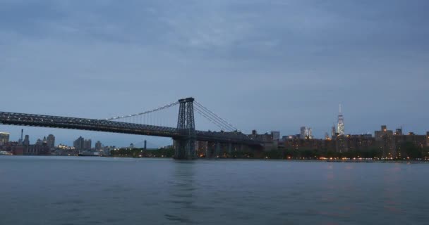 Een avond met de oprichting van de Williamsburg Bridge over de East River. — Stockvideo