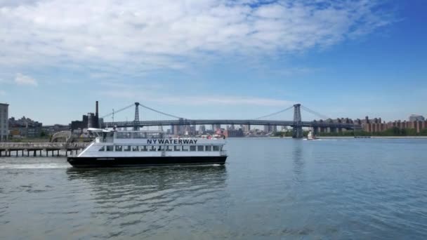 Blick auf die East River Fähre, die das Dock verlässt, mit der Williamsburg Brücke im Hintergrund. — Stockvideo