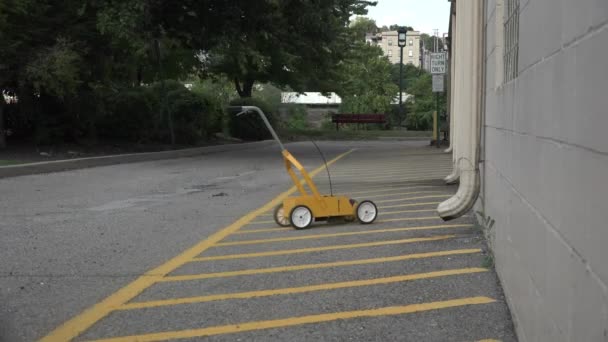 Una foto de un hombre pintando nuevas líneas amarillas en un estacionamiento . — Vídeos de Stock