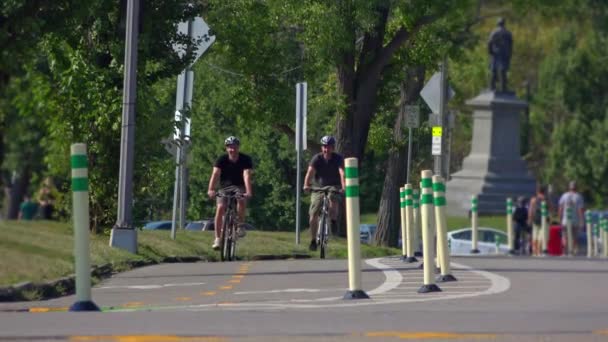 Dos chicos en edad universitaria montan sus bicicletas en un carril bici en Schenley Park en el área de Oakland de Pittsburgh, PA. Disparo a 60 fps . — Vídeo de stock