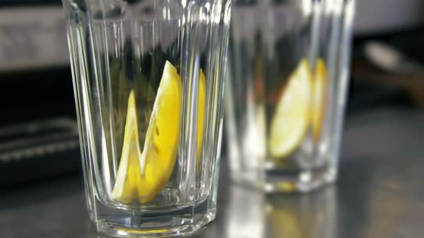 Cantinero echando limón, menta y mucho hielo en vasos — Vídeo de stock