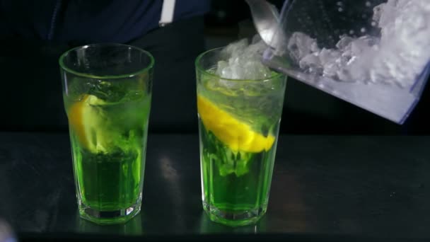 Bartender pouring ice and decorating two cocktails with mint — Stock Video