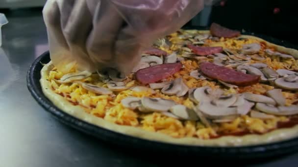 Dolly toma de pizzaiolo vertiendo salami en la pizza — Vídeos de Stock