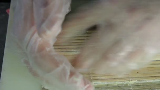 Rolling up the sushi roll with bamboo mat, close up view — Stock Video