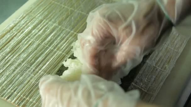 Cook making sushi rolls, spreading rice over nori, upside view — Stock Video