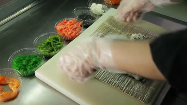 Cocinar haciendo rollos de sushi, esparciendo arroz sobre nori — Vídeos de Stock