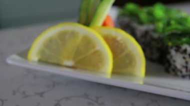 Wasabi, zencefil, limon ve deniz yosunu ile dekore edilmiş plaka üzerinde lezzetli suşi rulo