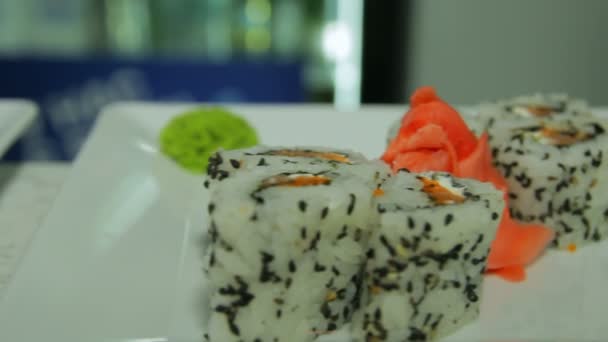 Dolly shot de deliciosos rolos de sushi na placa branca com wasabi e gengibre — Vídeo de Stock