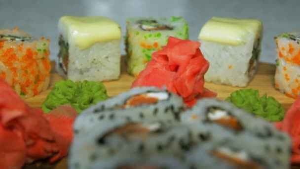 Dolly lövés a finom sushi tekercs a fából készült lemez, a wasabi és gyömbér — Stock videók