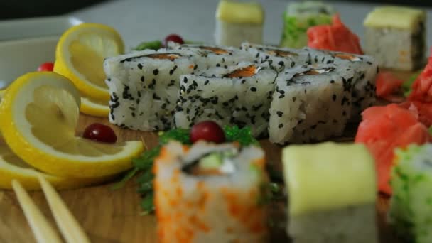 Dolly lövés a finom sushi tekercs a fából készült lemez, a wasabi és gyömbér — Stock videók