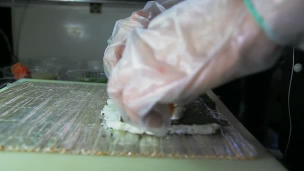 Dolly shot de chef adicionando salmão e pepino a rolos de sushi — Vídeo de Stock