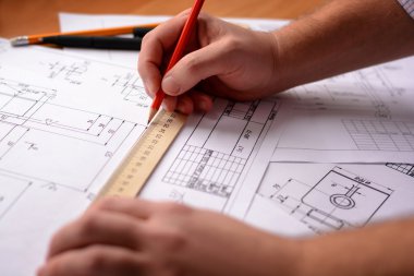 Adam mimar Ofis Masası, kağıt üzerine büyük kalem tarafından bir plan, grafik, tasarım, geometrik şekiller çizer. Yumuşak odak.