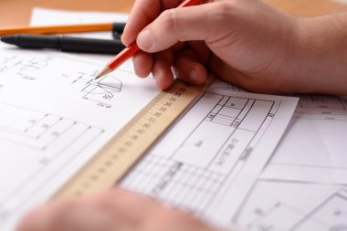 Adam mimar Ofis Masası, kağıt üzerine büyük kalem tarafından bir plan, grafik, tasarım, geometrik şekiller çizer. Yumuşak odak.