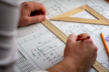 Adam mimar Ofis Masası, kağıt üzerine büyük kalem tarafından bir plan, grafik, tasarım, geometrik şekiller çizer. Yumuşak odak.