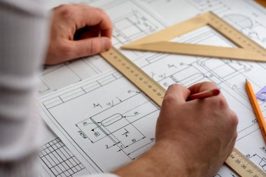 Adam mimar Ofis Masası, kağıt üzerine büyük kalem tarafından bir plan, grafik, tasarım, geometrik şekiller çizer. Yumuşak odak.