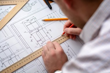 Adam mimar Ofis Masası, kağıt üzerine büyük kalem tarafından bir plan, grafik, tasarım, geometrik şekiller çizer. Yumuşak odak.